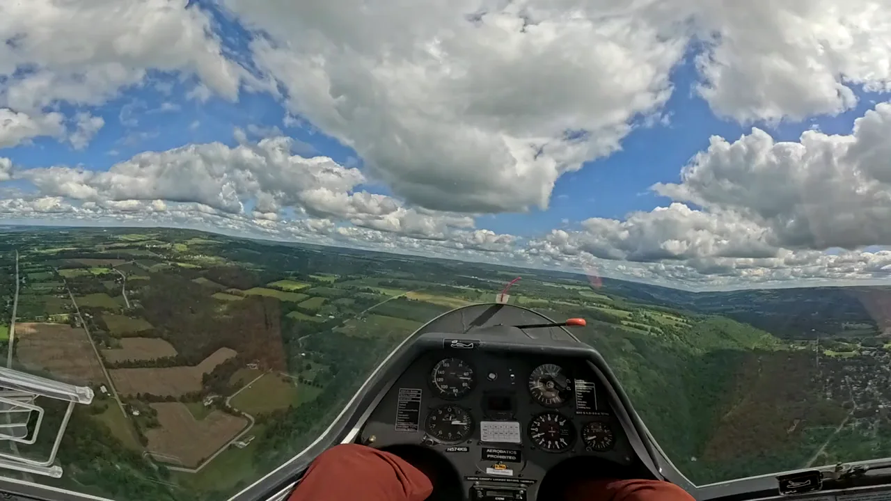 A cockpit view over fields and countryside from a sailplane in flight